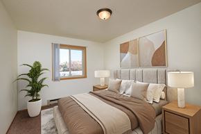 Fargo apartment for rent - a bedroom with a large bed and a potted plant. Fargo, ND Sargent Apartments