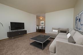Fargo apartment for rent - a living room with a couch, coffee table, and tv with the dining room in the background. Fargo, ND Southwind Apartment