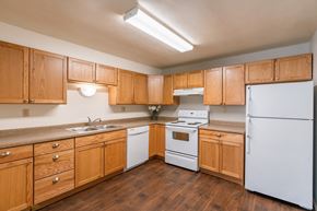 Fargo apartment for rent - a kitchen with white appliances and wooden cabinets. Fargo, ND Spring Apartments