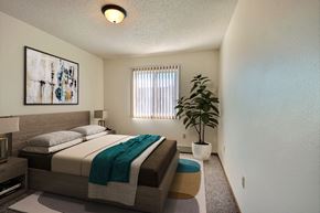 Fargo apartment for rent - a bedroom with a bed and a potted plant. Fargo, ND Sterling Park Apartments