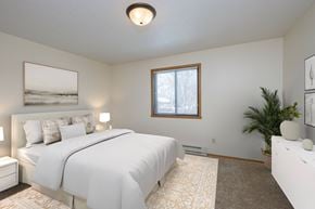 Fargo apartment for rent - Fargo, ND Sugar plum apartments. A bedroom with a large white bed, white dresser, and white night stands with a lamp on each,  and window.