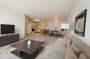 Fargo apartment for rent - Fargo, ND Thunder Creek Apartments. The room is furnished with comfortable seating, a coffee table, and tasteful decor, creating a warm and inviting atmosphere for relaxation and entertainment. A dining room and kitchen are in the background