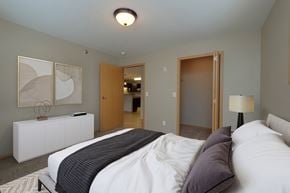 Fargo apartment for rent - a bedroom with a bed and a door to a bathroom. Fargo, ND Urban Plains Apartments