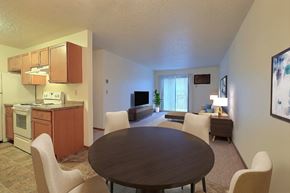 Fargo apartment for rent - a dining area with a table and chairs and a kitchen in the background. Fargo, ND Village West Apartments