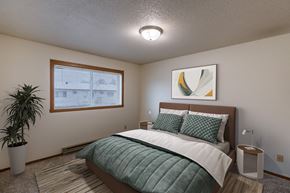 Fargo apartment for rent - a bedroom with a bed and a potted plant. Fargo, ND West Oak Apartments