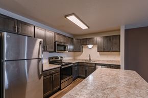 Fargo apartment for rent - a kitchen with stainless steel appliances and dark wood cabinets. Fargo, ND Willow Park Apartments