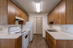 Fargo apartment for rent - an empty kitchen with white appliances and wooden cabinets. Fargo, ND Windsor Apartments