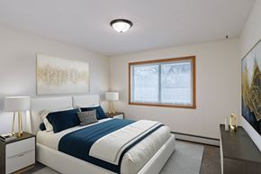 Fargo apartment for rent - a bedroom with a white bed and a blue and white comforter. Fargo, ND Windsor Apartments
