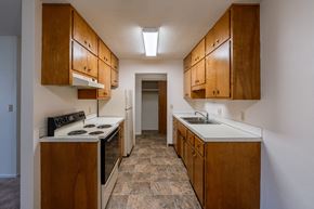 Fargo apartment for rent - a kitchen with white appliances and wood cabinets. Fargo, ND Woodland Apartments