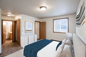 Fargo apartment for rent - a bedroom with a white bed and a blue blanket. Fargo, ND Cedar Pointe Apartments