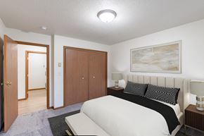 Fargo apartment for rent - a bedroom with a bed and a closet and a door to a bathroom. Fargo, ND Flagstone Apartments