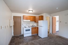 Fargo apartment for rent - an empty kitchen with white appliances and wooden cabinets.Fargo, ND Forest Avenue Apartments