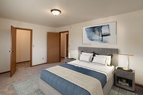 Fargo apartment for rent - a bedroom with a bed and a door to a closet. Fargo, ND Hunters Run 2 Apartments