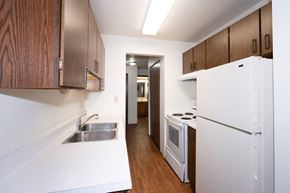 Fargo apartment for rent - a kitchen with white appliances and wooden cabinets and a white refrigerator. Fargo, ND Pacific Park Apartments