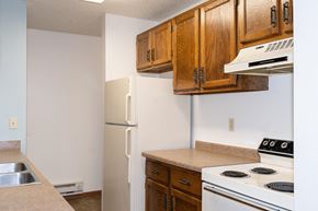 Fargo apartment for rent - a kitchen with white appliances and wooden cabinets and a refrigerator. Fargo, ND Pacific South Apartments