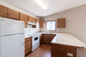 Fargo apartment for rent - an updated kitchen with white appliances and wooden cabinets. Fargo, ND Rosegate Apartments