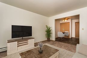 Grand Forks triplex for rent - Grand Forks, ND Amberwood Apartments. A living room with a tv and a dining room in the background