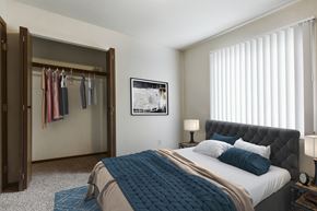 Grand Forks apartment for rent - Grand Forks, ND Carling Manor Apartments.  a bedroom with a large bed and a closet with a sliding door and a window
