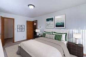 Grand Forks apartment for rent - a bedroom with a bed and two lamps and a door to a bathroom. Grand Forks, ND Cedarwood Apartments