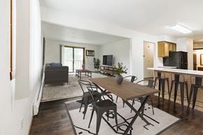 Grand Forks apartment for rent - Grand Forks, Chandler 1802 Apartments. An dining room with a dining table and chairs and a living room with a couch and tv in the background