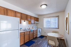 Grand Forks apartment for rent - a kitchen with a dining table and a refrigerator. Grand Forks, ND Chandler 1898 Apartments