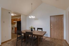 Grand Forks apartment for rent - A dining room and kitchen with a wooden table and chairs. Grand Forks, ND Creekside Apartments.