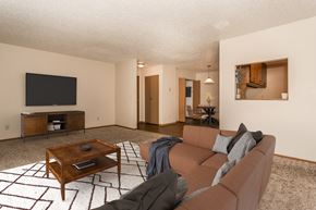 Grand Forks apartment for rent - Grand Forks Kremer Apartments  A living room with a couch, coffee table, and tv with a dining area in the background