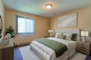 Grand Forks apartment for rent - a bedroom with bed, dresser, and a window. Grand Forks, ND Madison Apartments