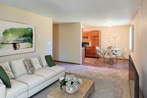 Grand Forks apartment for rent - a living room with a couch and a coffee table in front of a dining room. Grand Forks, ND Madison Apartments