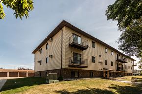 Grand Forks apartment for rent - Grand Forks Ridgemont Apartments. An exterior of a three level apartment building with garages in the background.