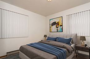 Grand Forks triplex for rent - Grand Forks, ND Valley Home Duplex. a bedroom with two windows and a bed with a gray blanket and blue pillows