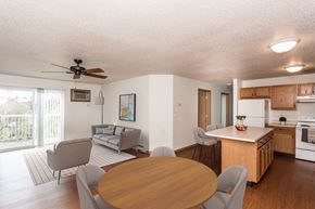 Grand Forks apartment for rent - Grand Forks, ND Vista Apartments. A living room and dining room with a couch, chair, and table with the kitchen in the background.