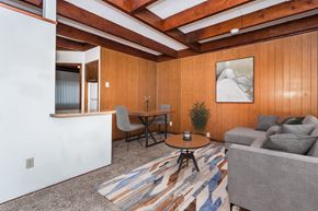 Grand Forks apartment for rent - Grand Forks, ND Washington Apartments a living room with wood paneling and a beamed ceiling with a couch and dining area in the background