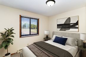 Hutchinson apartment for rent - a bedroom with a bed and a window and a plant. Hutchinson, MN Echo Manor Apartments