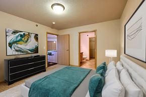 Fargo apartment for rent - a master bedroom with a bed and a tv. Fargo, ND East Bridge Apartments