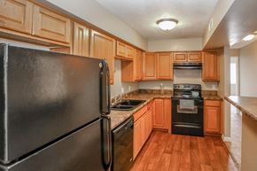 Omaha apartment for rent - a kitchen with wooden cabinets and appliances and a black refrigerator. Omaha, NE Evergreen Terrace Apartments