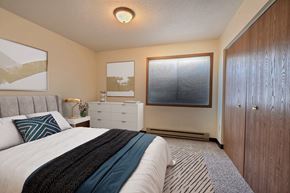 Fargo apartment for rent - a bedroom with a bed and a dresser and a window. Fargo, ND Prairiewood Meadows Apartments