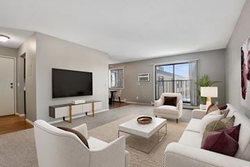 St. Louis Park apartment for rent - St Louis Park, MN Edge of Uptown Apartments. a bright living room with gray walls, a large tv on the wall, and white furniture. A large slidinng glass dooor allows suunlught to flood into the room.
