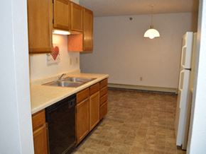 Moorhead apartment for rent - a kitchen with white appliances and wooden cabinets. Dilworth, MN Fieldstone Apartments