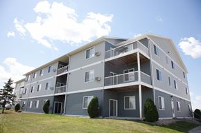 West Fargo apartment for rent - An exterior view of a gray apartment building with balconies. West Fargo, ND West Lake Apartments.