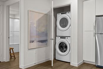 A white washer and dryer in a closet with a door