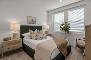 An empty bedroom with a bed and two windows
