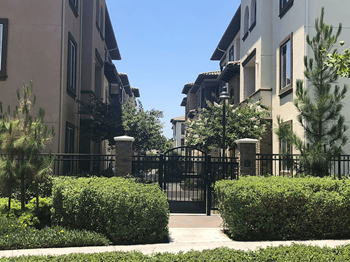 Gated community entrance with manicured hedges and walkway