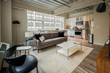 Chicago apartment for rent - A modern living room with a grey sofa and a black chair.