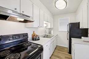 Denver apartment for rent - A kitchen with a black stove top oven and white cabinets.