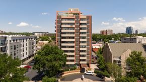 Denver apartment for rent - A tall building with a red frame stands in the middle of a city.
