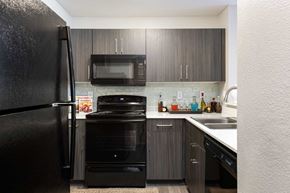Las Vegas apartment for rent - a kitchen with black appliances and dark wood cabinets