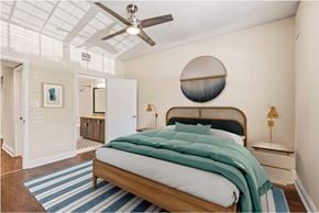 Hollywood apartment for rent - A bedroom with a bed, a ceiling fan, and a round mirror on the wall.