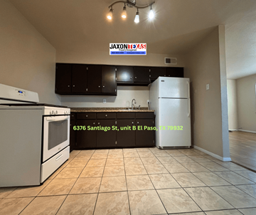 El Paso apartment for rent - A kitchen with a white refrigerator and black cabinets under a JAXONBYS sign.
