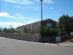 El Paso apartment for rent - A street view with a house, a lamp post and a stone wall.